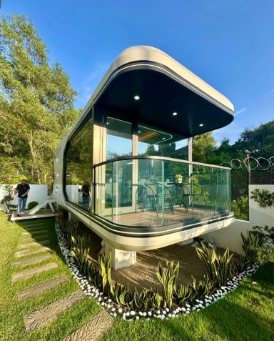 Moderne Architektur mit verglastem Balkon und umgeben von einem gepflegten Garten.