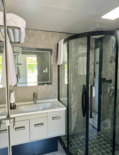 Helles Badezimmer mit Dusche, Waschbecken und Spiegel, moderne Ausstattung.